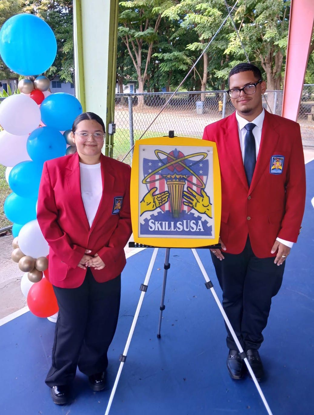 Dos representantes estudiantiles de la Miguel Such junto al emblema de SkillsUSA durante la competencia de 2026 en Arecibo.